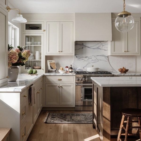 Neutral Inset Kitchen Cabinets with Glass-Front Units Neutral tone kitchen with inset cabinets, glass-front wall units, and flush door construction