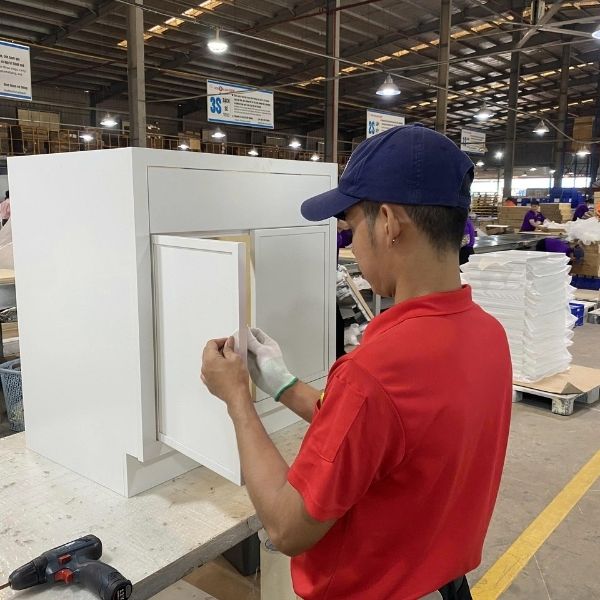 worker assembling kitchen cabinet door during cabinet construction process