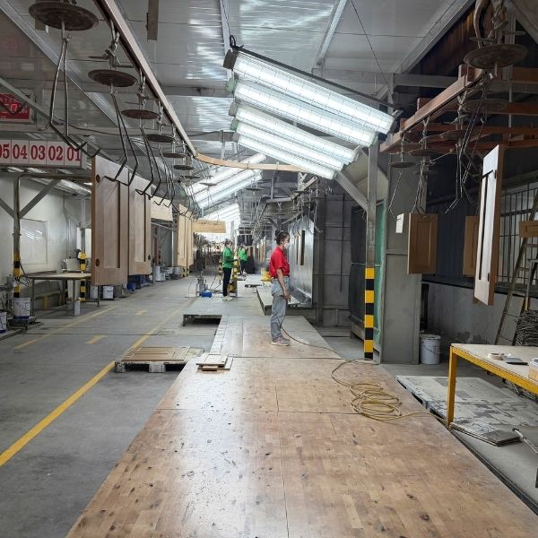 Factory inspector checking painted cabinet finish surface under controlled lighting conditions