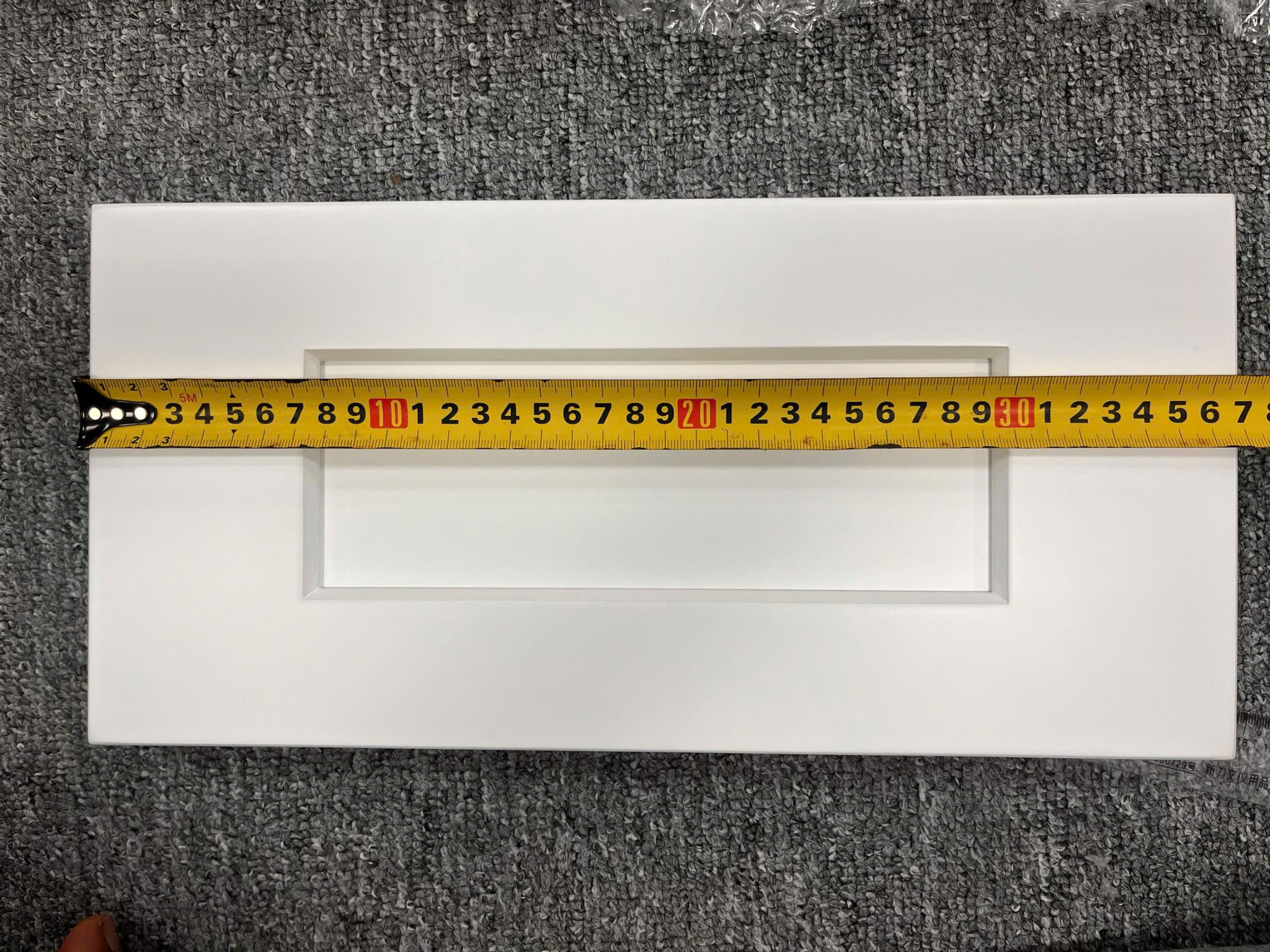 Digital caliper measuring cabinet door panel thickness to verify cabinet tolerances in factory production